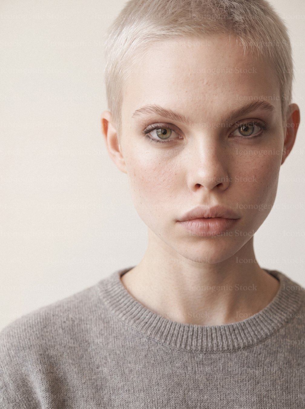 Portrait of a young woman with buzz cut hair and freckled skin, neutral expression