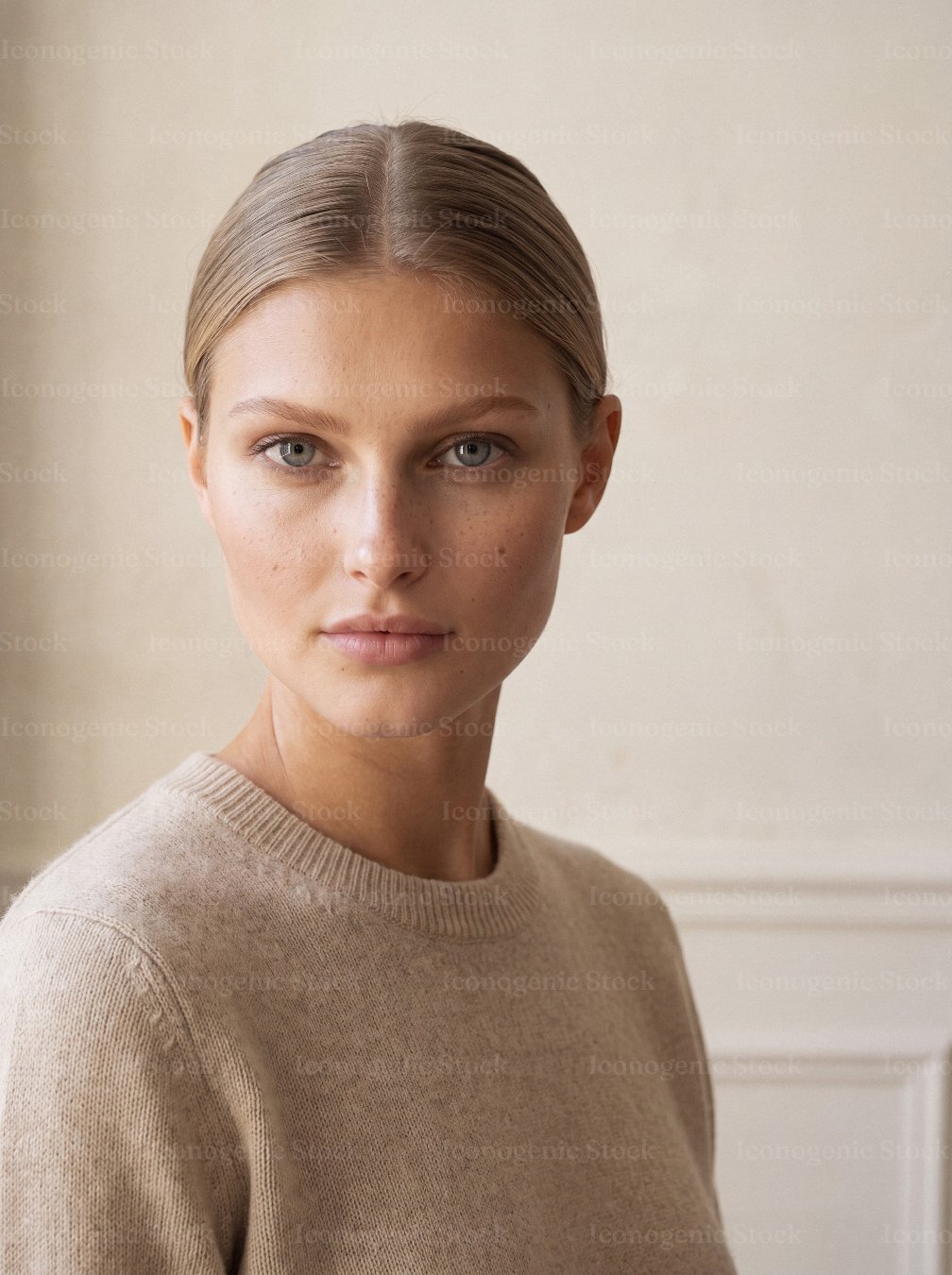 Portrait of young woman with slicked back hair wearing beige sweater indoors