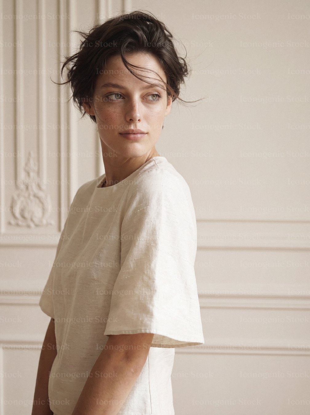 Portrait of elegant young woman in beige linen top against classic wall