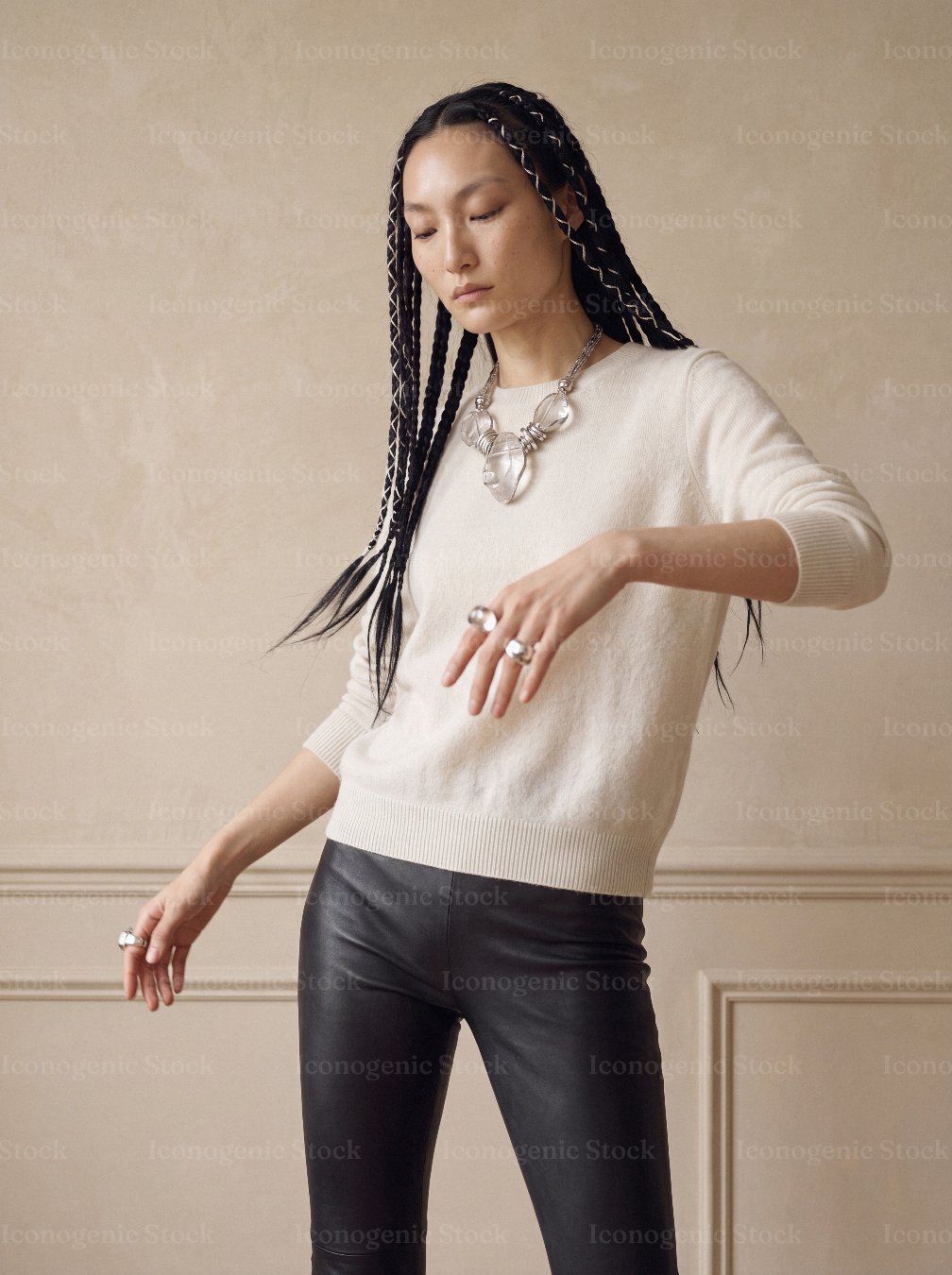 Fashion model with braided hair posing in cream sweater and statement jewelry