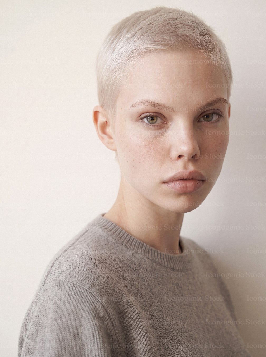 Young woman with short platinum blonde hair in neutral portrait, natural skin texture