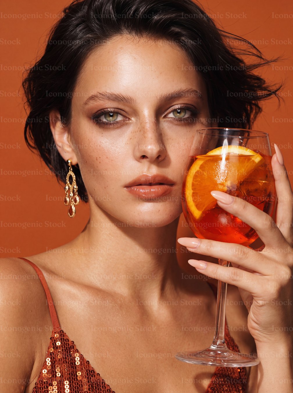 Elegant Woman Holding Aperol Spritz Cocktail Glass with Orange Slice on Orange Background