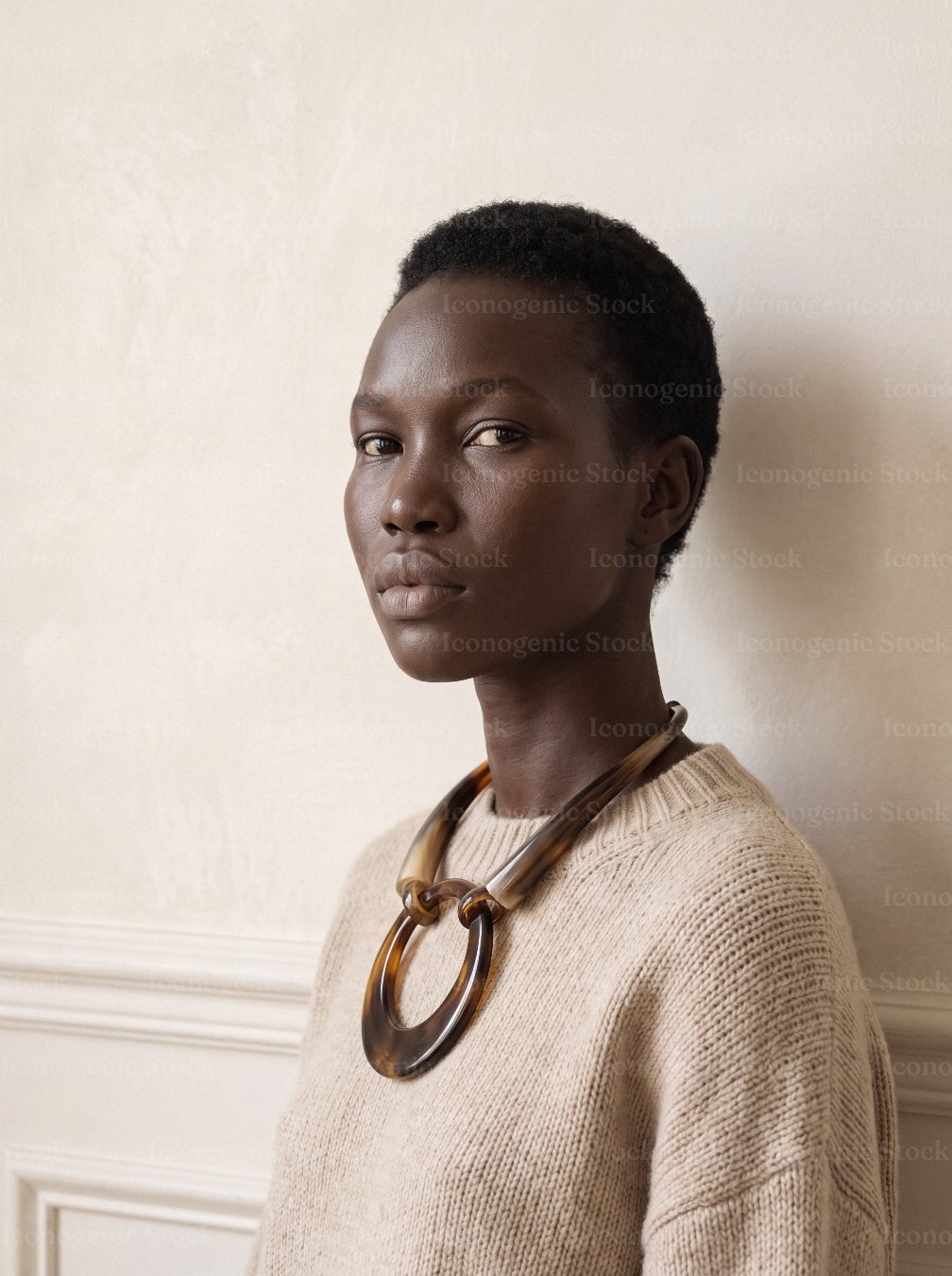 Portrait of woman with short hair wearing tortoiseshell necklace and beige knit sweater