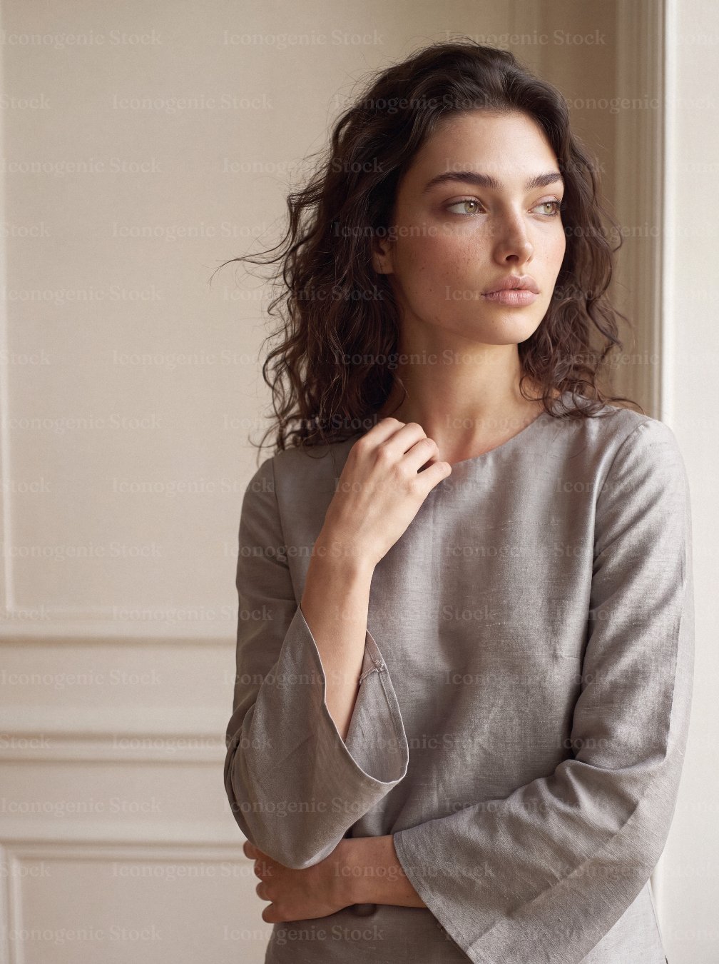 Elegant woman in neutral silk blouse gazing thoughtfully by window light