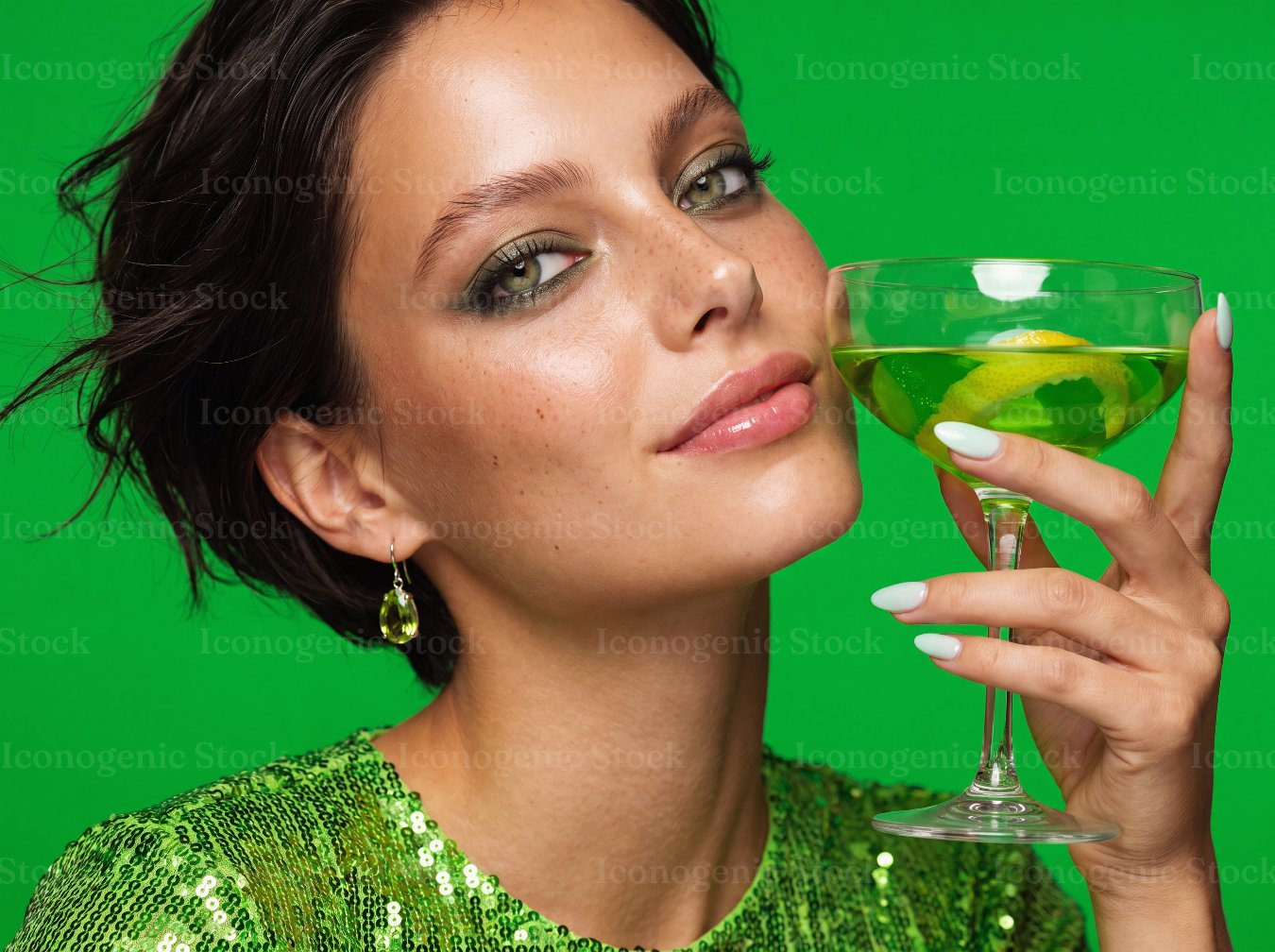Woman in green sequin dress holding cocktail glass on green background