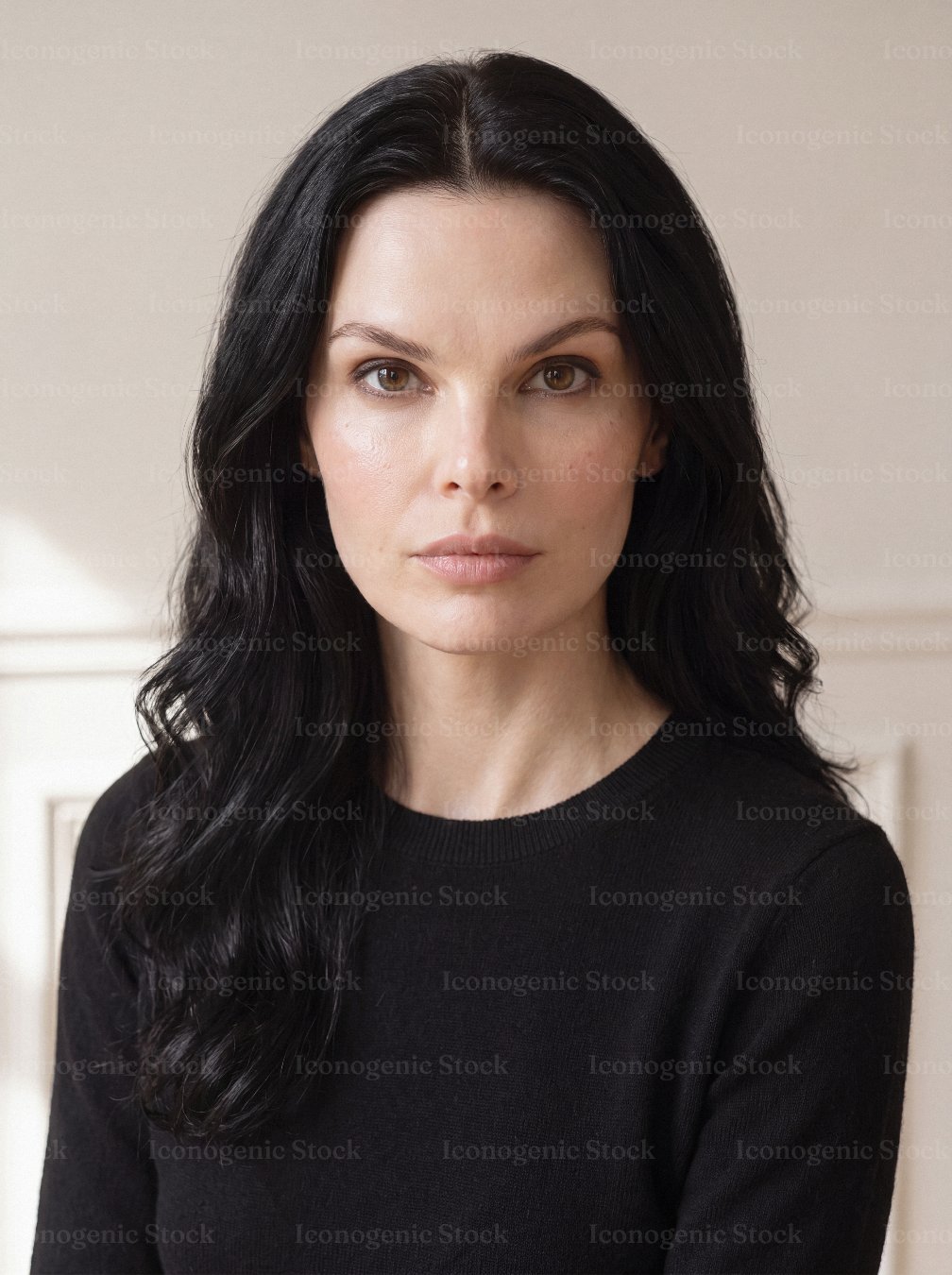 Serious woman with long dark hair wearing black sweater looking at camera indoors