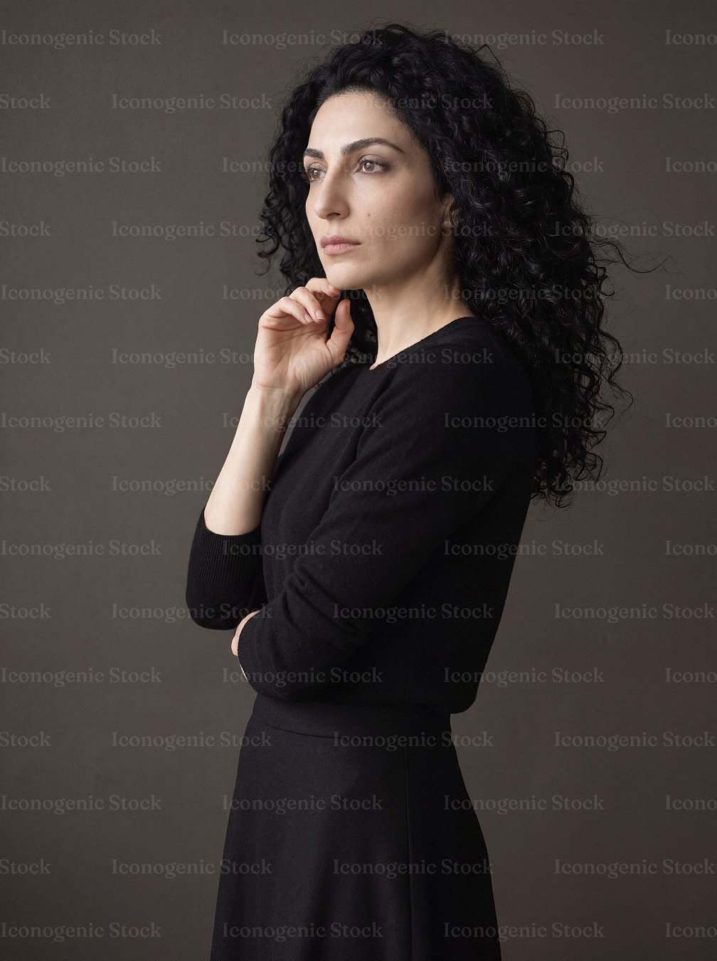 Elegant woman with curly dark hair in black dress, thoughtful side profile portrait