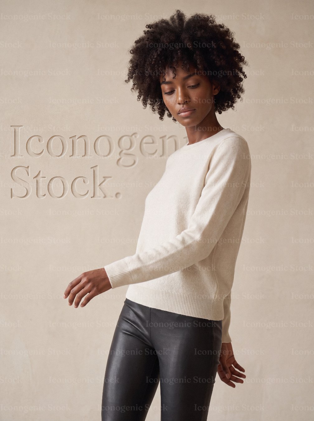 Fashion portrait of woman with curly afro hair wearing cream sweater and leather leggings