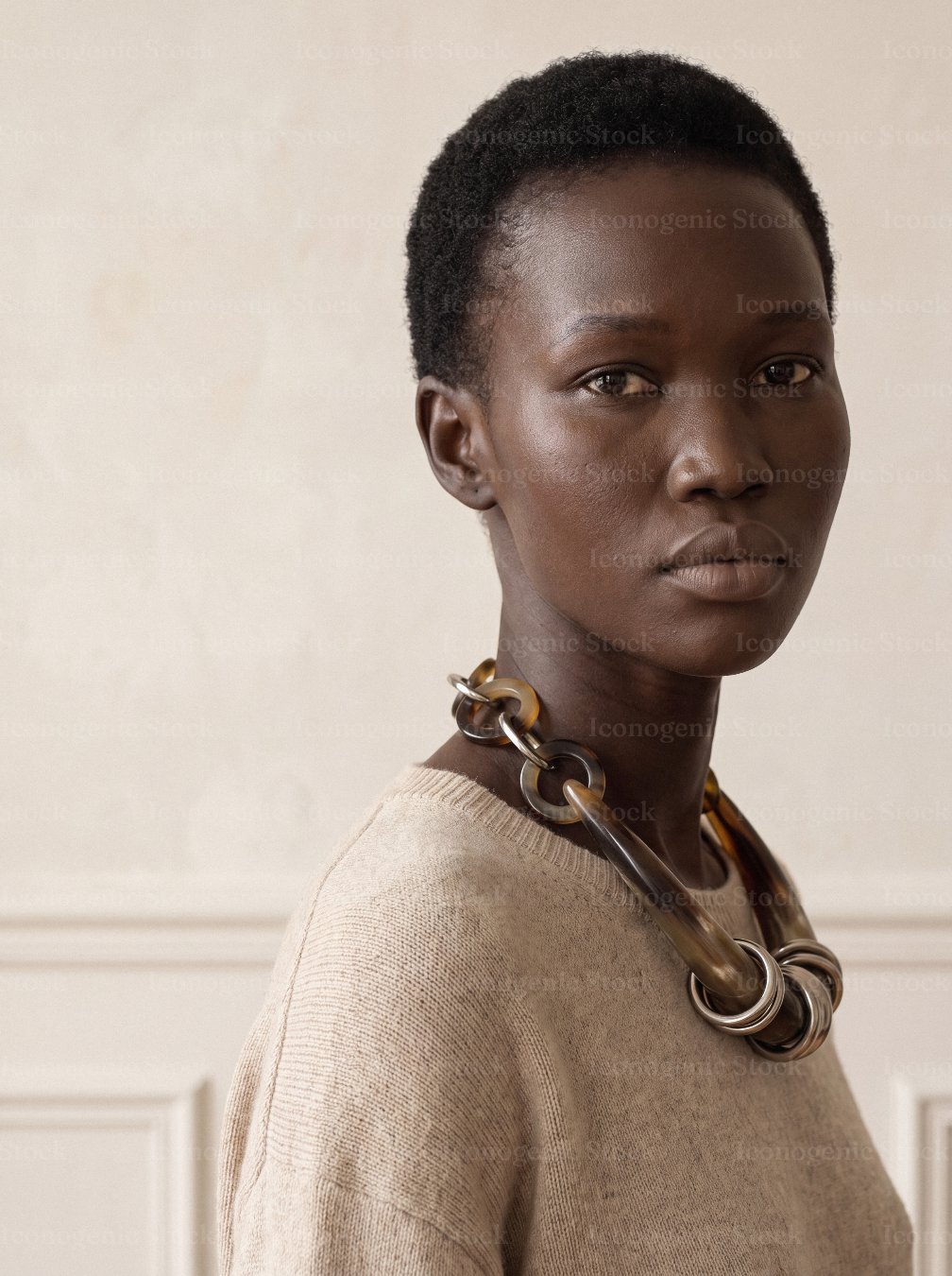 Portrait of a woman with short hair wearing a bold chunky chain necklace and beige sweater