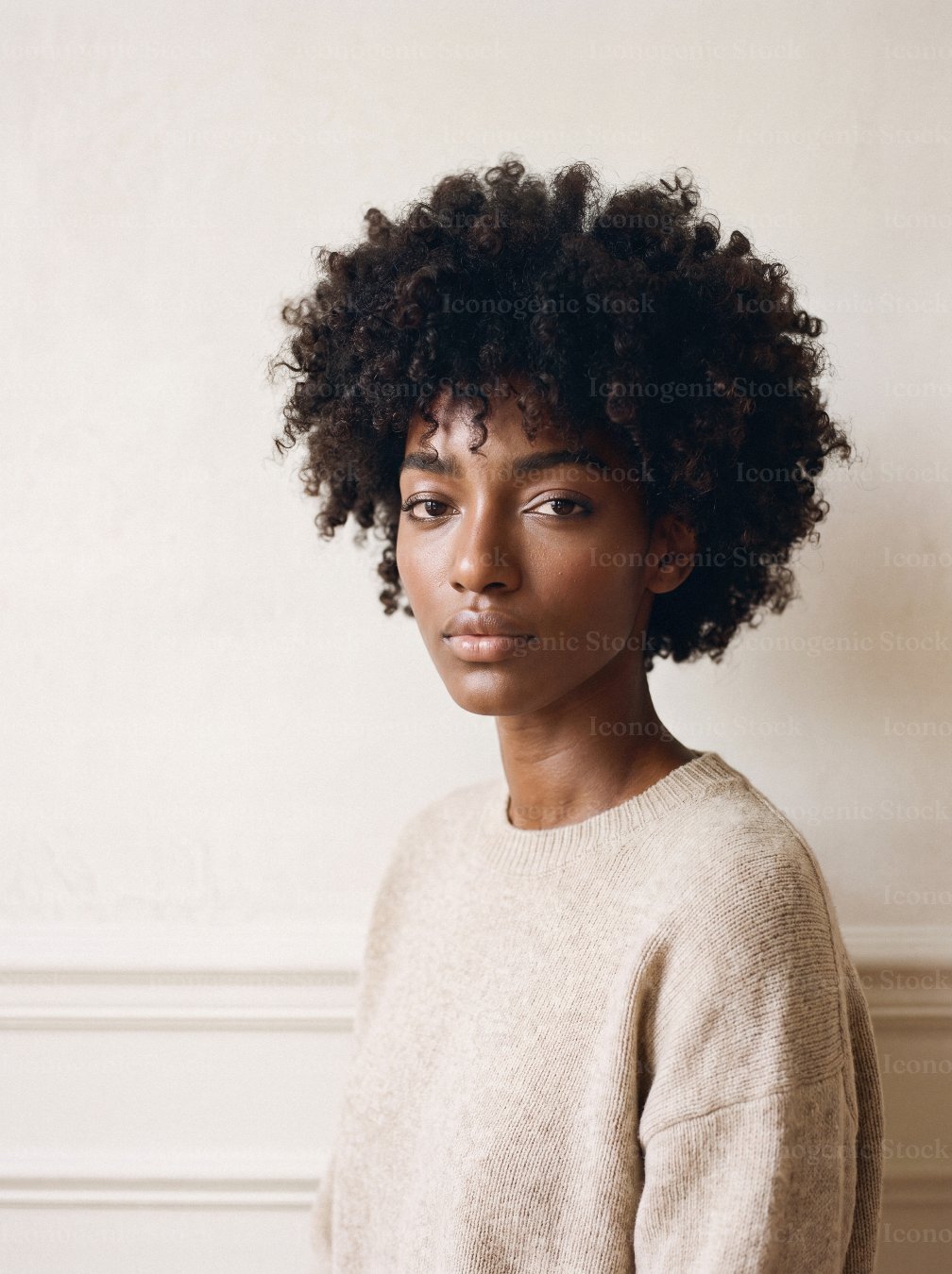 Portrait of young woman with curly afro hair wearing beige knit sweater