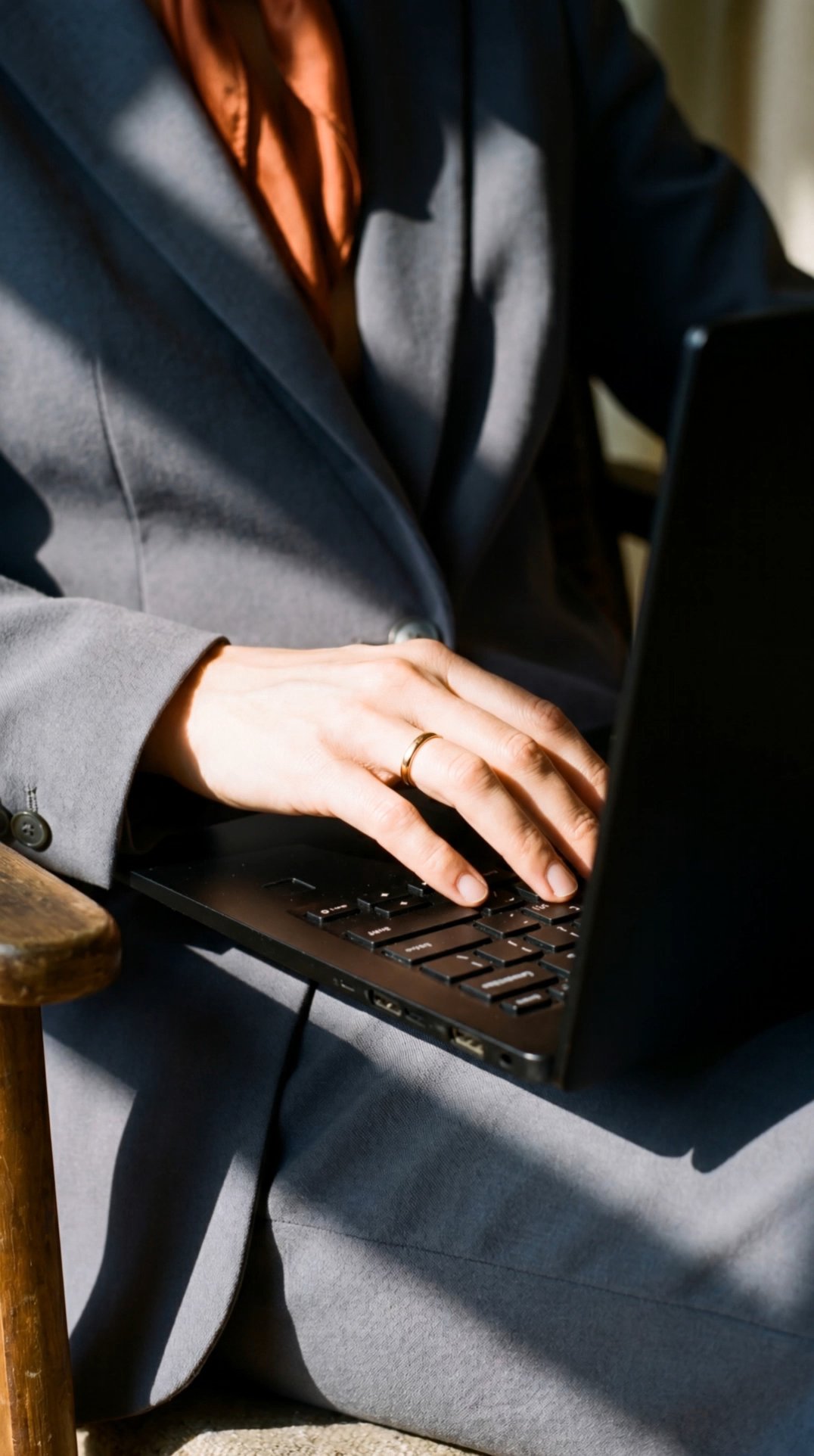 Businesswoman typing on laptop keyboard, close-up of hand wearing gold ring